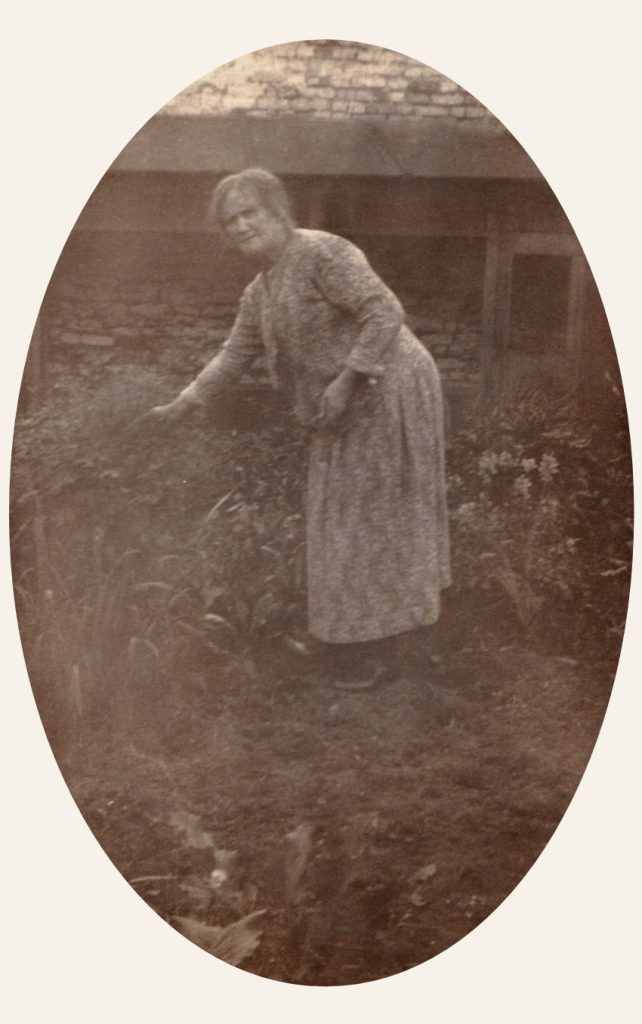 Old postcard with an image of a lady gardening in front of a house