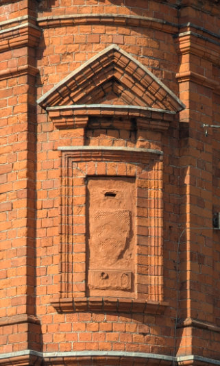Close up view of a red brick building that features a very faded Villa Cardiff crest.